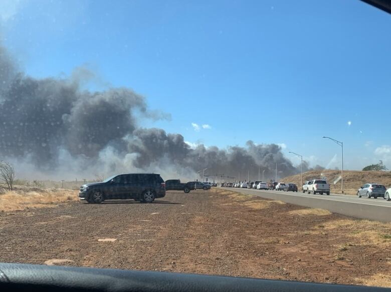 Smoke billows over a line of cars in Maui, Hawaii