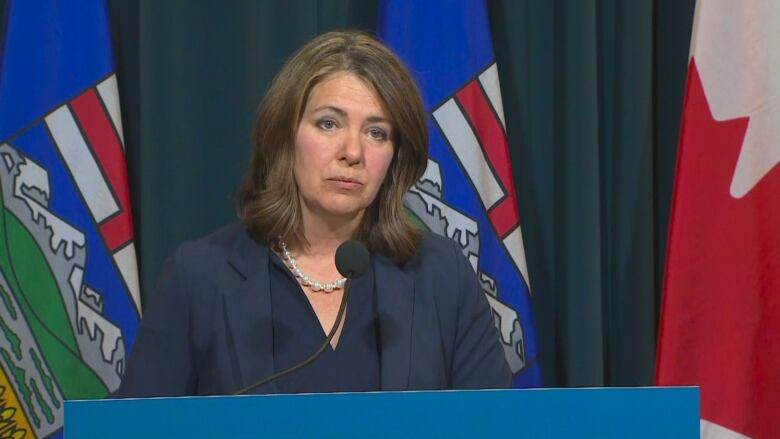 A woman speaks in front of a podium.