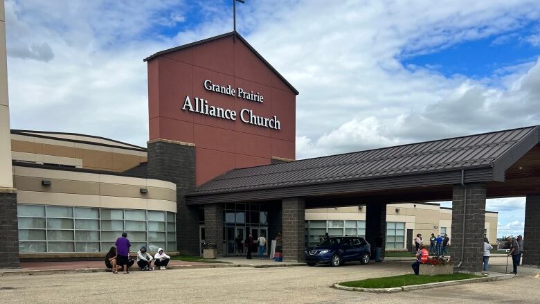 A building is seen across a parking lot, with 'Grande Prairie Alliance Church' written on the building.