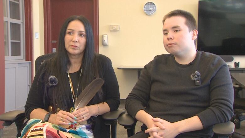 Michelle Peters is sitting down next to her son Ssep Patfield in an office space.