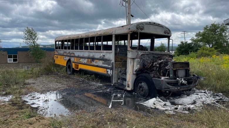 A burned out school bus sits in a grassy field in Baddeck, N.S. 