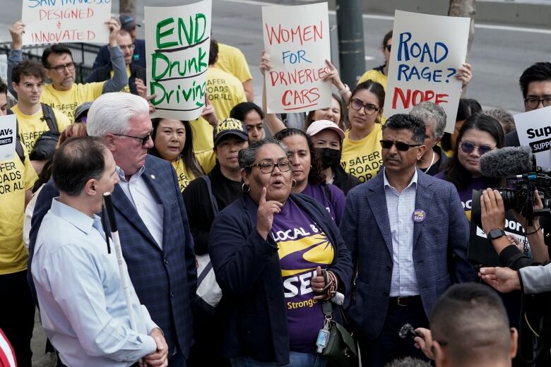 A group of people gathered outside wielding signs that read, 'Women for driverless cars, 'Road rage? Nope' and 'End Drunk Driving.'