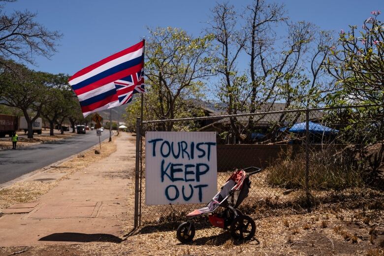 A sign that says 'Tourist Keep Out' is seen next to a Hawaiian flag.