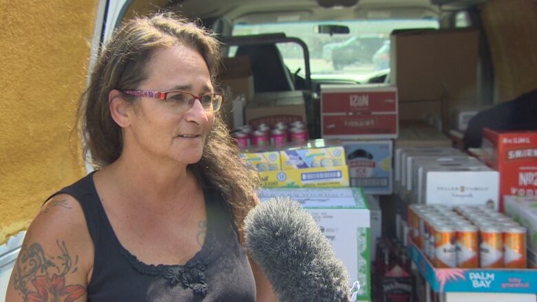 A woman stands at the back of a van that is filled with boxes