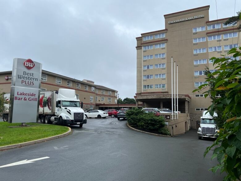 A large hotel building and parking lot filled with vehicles on a cloudy day. A sign says Best Western Plus.