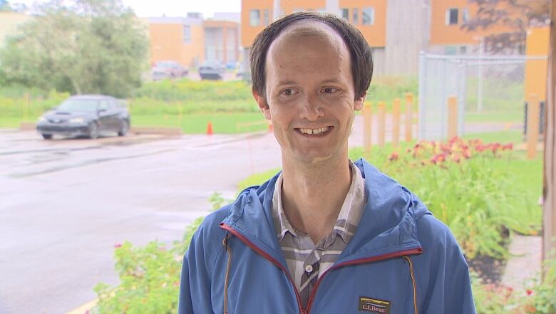 man smiling, shrubs in background