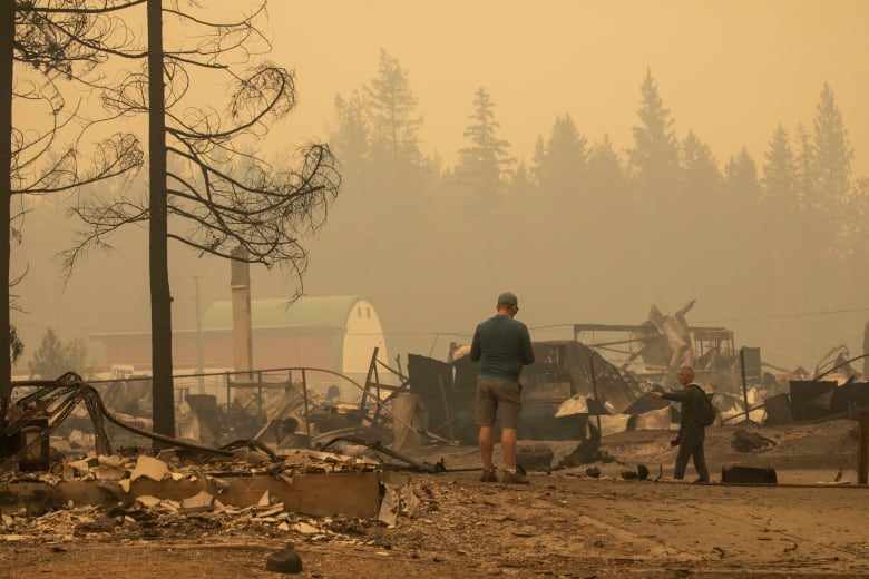 Two men walk through a pile or rubble.