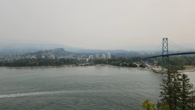 Hazy conditions obscure buildings next to a water body, with a bridge visible on the right.