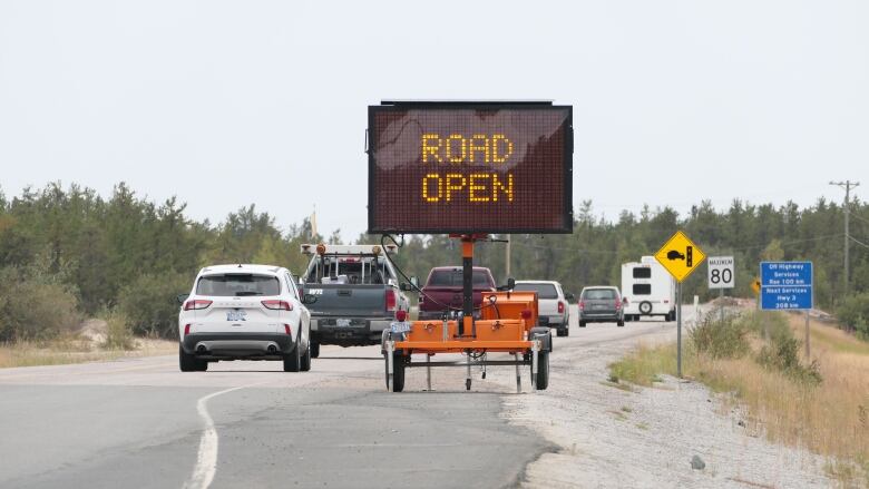 Vehicles on a highway behind a sign saying 