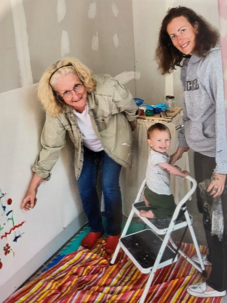 Three generations of women in a family smile for a photo in a playroom.