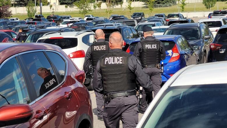 Police officers search in a parking lot.