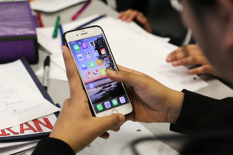 Teenagers are shown on cellphones, in closeup. 