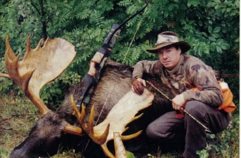 man standing next to a moose he hunted 