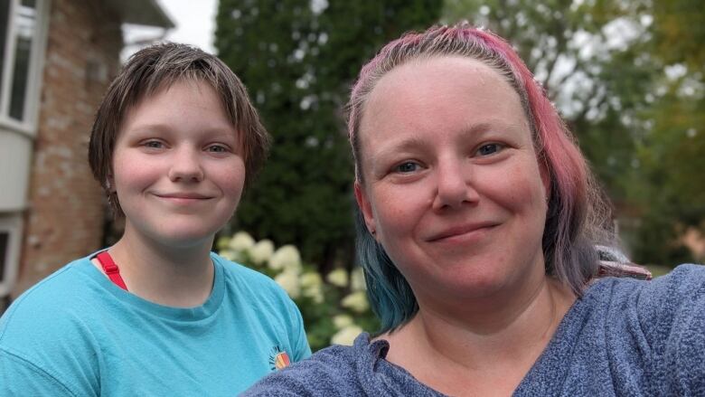 A teen and their mom pose for a selfie.