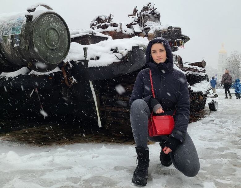 Sakhnatska kneeling in the snow by a destroyed Russian tank in central Kyiv when she returned to Ukraine the first time during the war.