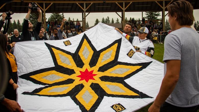 A large starblanket is gifted to a young man.