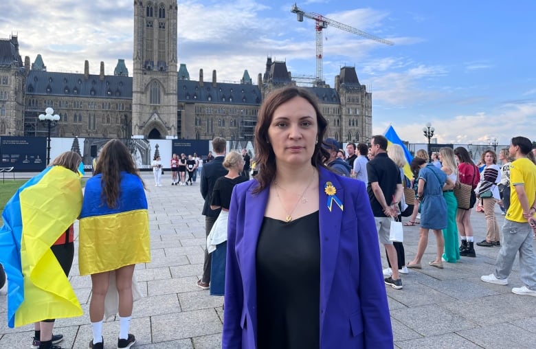 An ambassador poses for a photo on a legislature's lawn.