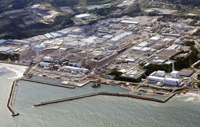 An aerial view of a nuclear facility alongside the ocean. 