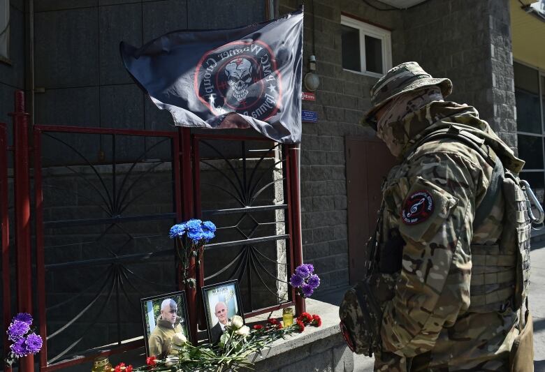 A fighter of Wagner private mercenary group lights a candle at a makeshift memorial with portraits of Russian mercenary chief Yevgeny Prigozhin and Wagner group commander Dmitry Utkin outside the local office of the Wagner private mercenary group in Novosibirsk, Russia August 24, 2023.