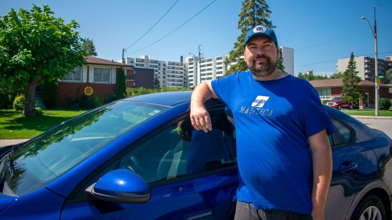 A man leaning on a car.