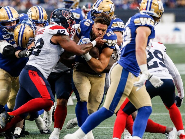 A football player pushes through a crowd and he is tackled by another player