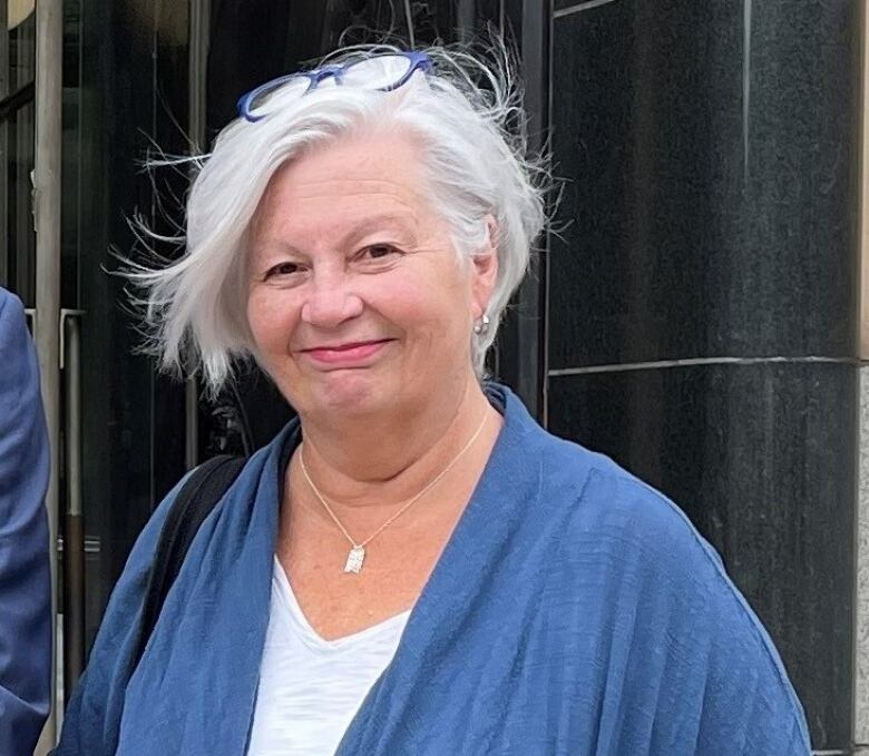 A woman wearing a blue and white top poses for a photo.