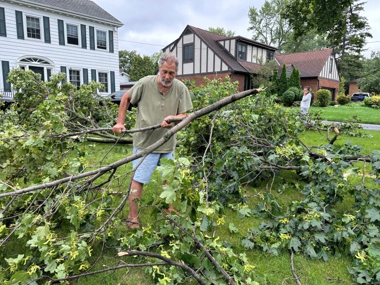 Todd Cook, a homeowner in the 5400 block of Riverside Drive East, moves some of the many fallen branches on his property on Aug. 25, 2023.