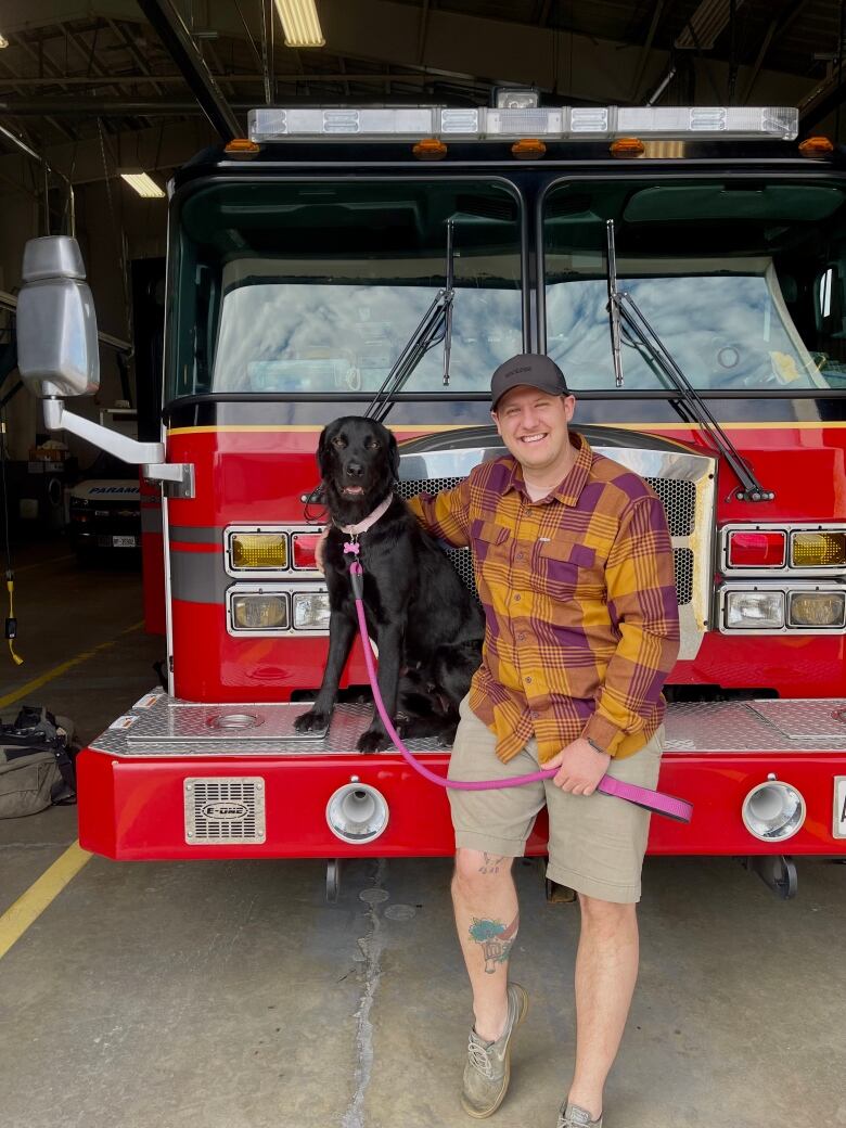 A man and a dog standing in front of a fire truck