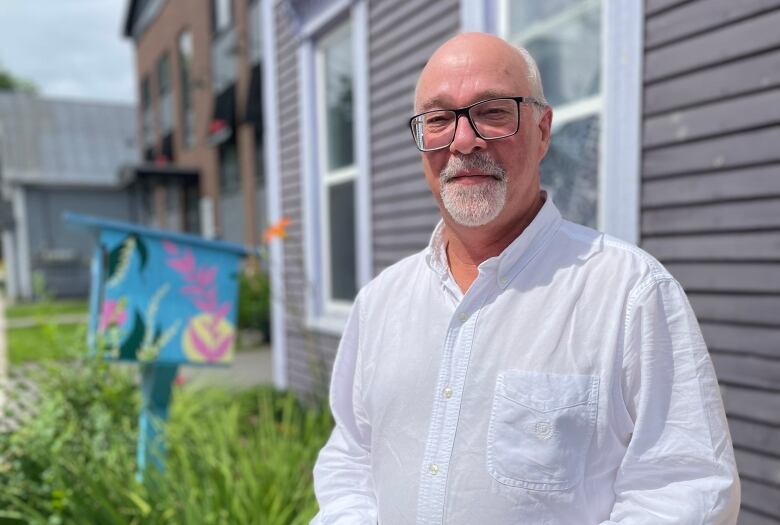 A man with a white beard and glasses and a white dress shirt.