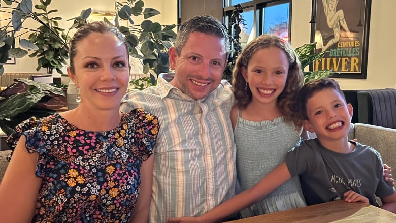 A woman, man and two children sit smiling at a table. 