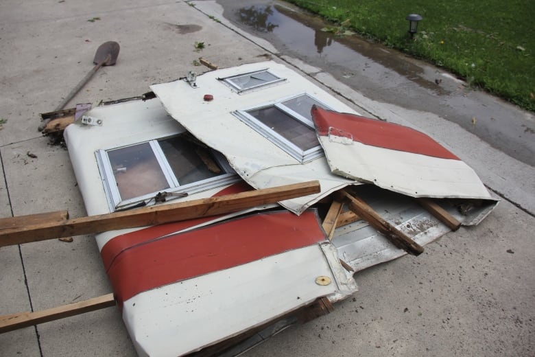 The metal side of a trailer folded in on itself on the ground. 