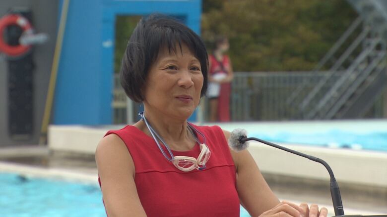 Mayor Olivia Chow standing in front of a pool at a podium. 