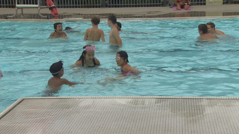 Mayor Olivia Chow pictured wearing goggles and speaking to kids in a pool 