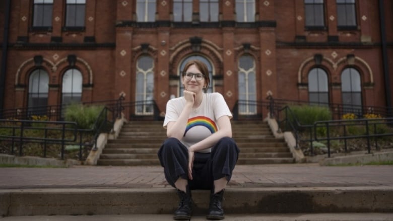 A woman sits on the front steps in front of a school