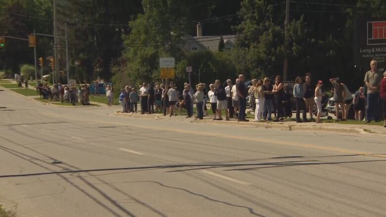 People standing on the side of a road. 