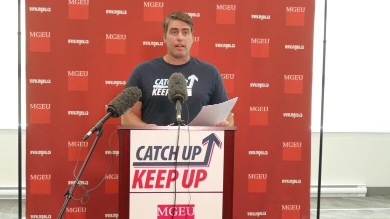 A man speaks into a microphone behind a podium.