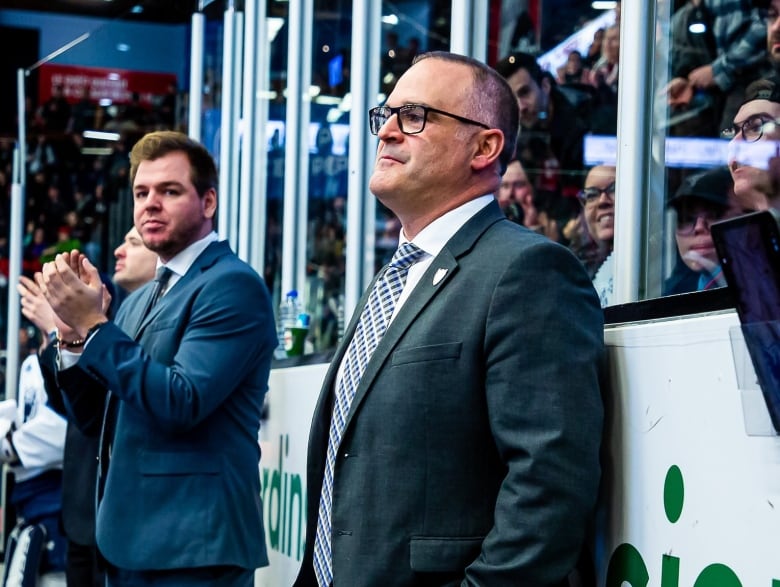 A head coach stands at the bench of a hockey game in the Quebec Major Junior Hockey League