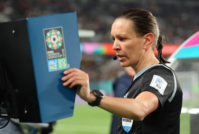 A soccer ref is looking at a video screen to check one of her decisions.