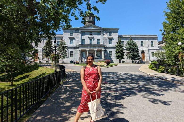 A woman stands outside in front of a stone building.