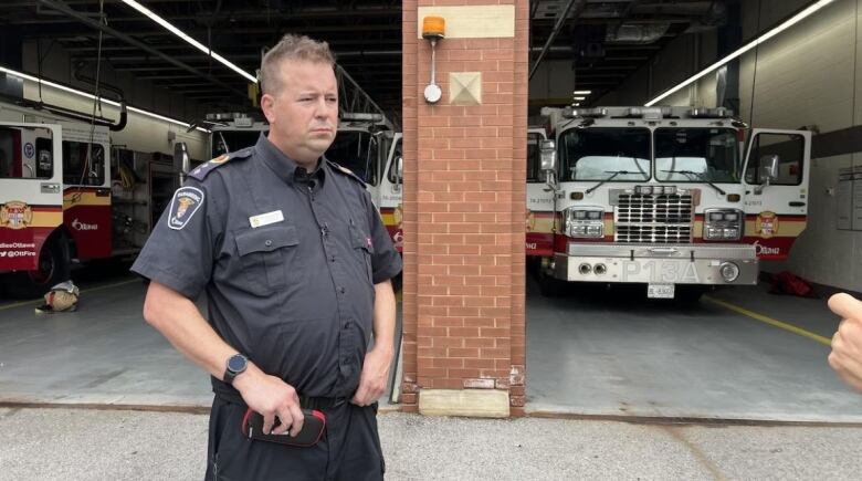 A paramedic does an interview in front of a fire station in summer.