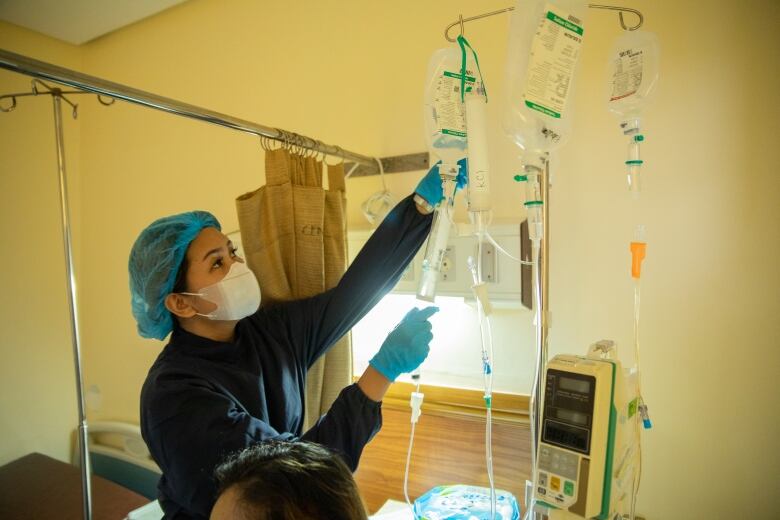 A nurse attends to an IV.