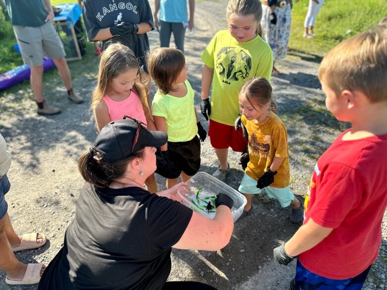 Children gather around a baby turtle.