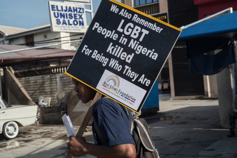 A man holds a protest sign over his shoulder that reads 