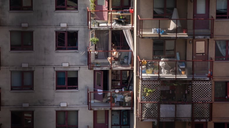 A woman sits on her balcony during a hot period of weather.