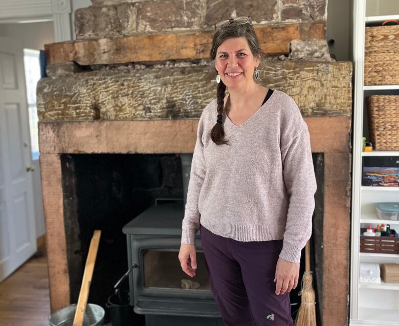 woman standing in front of stone fireplace smiling