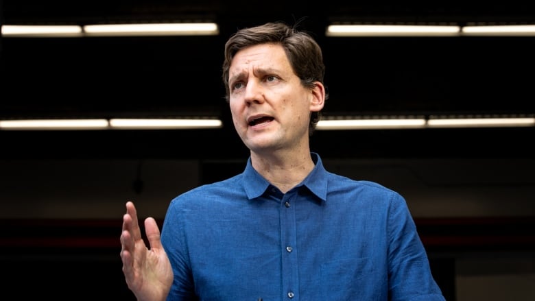 A man in a blue shirt raises his hand and speaks.