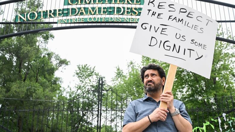 man with sign outside cemetery