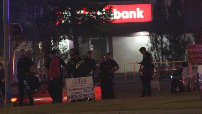 Officers stand with shields in front of a Scotiabank. 