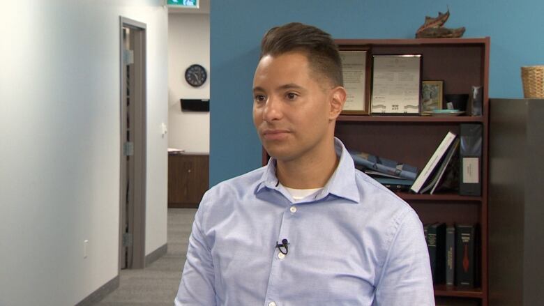 A man in a blue dress shirt looks at the camera in an office