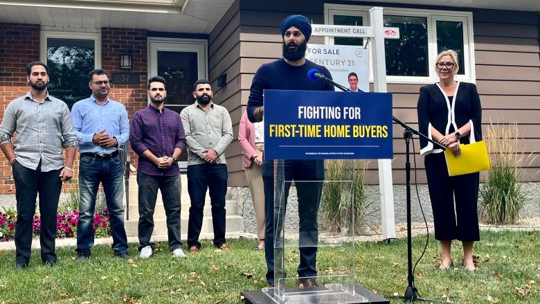 Several people stand in front of a one-story home.